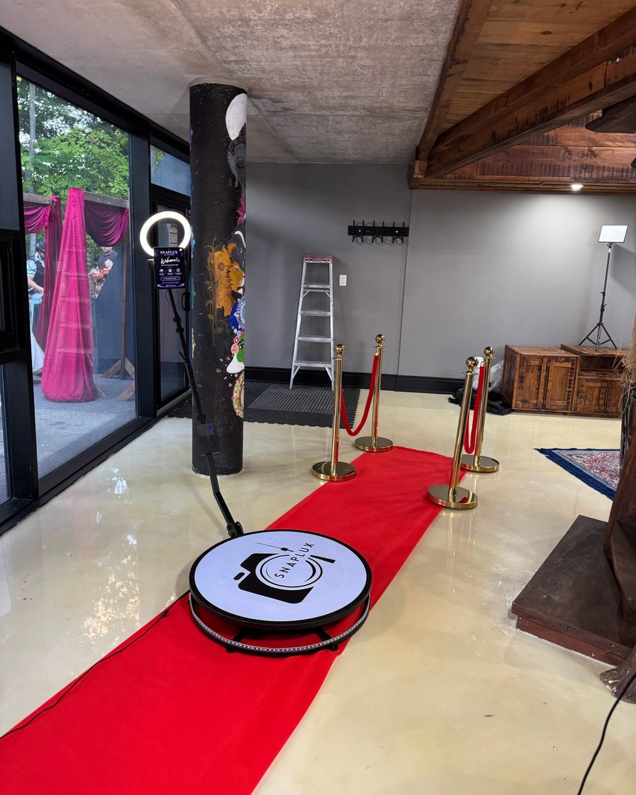 The SnapLUX 360 booth platform on a red carpet with gold stanchions and a ring light